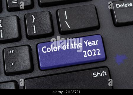 Color of the year 2022 key on a black pc keyboard. Computer notebook enter key of blue violet trendy color  very peri. Message on the pc enter button. Stock Photo