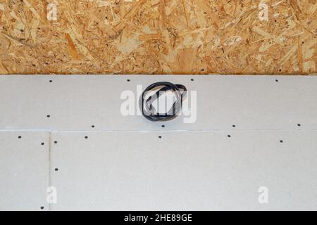 an electrical cable protruding from the plasterboard wall for the installation of lighting and air conditioning. Home repairs. Stock Photo