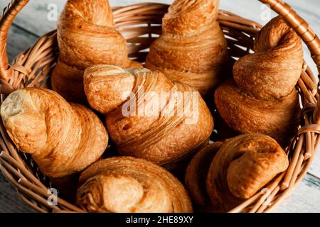 Croissants in a wicker basket on a wooden background. Closeup. Stock Photo