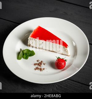 Strawberry cheesecake on a white plate. Black wooden background. Stock Photo