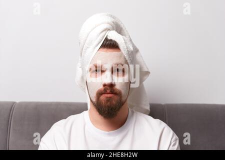 Portrait of man in white tshirt applying clay mask on his face. Self care morning spa procedure Stock Photo