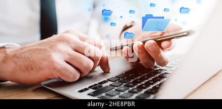 Document management system (DMS) concept, businessman using laptop and smartphone in office work, digitally enhanced image with selective focus Stock Photo