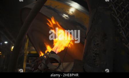Close up of firing process in the hot shop of the factory. Industrial background with rotating shaft being fired at the iron casting plant. Stock Photo