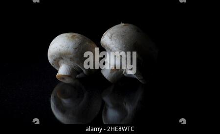 Champignons on a black background. Frame. Two mushrooms isolated on black reflective background Stock Photo