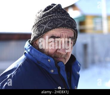 Portrait of old Russian man looking sadly in the camera on winter background Stock Photo