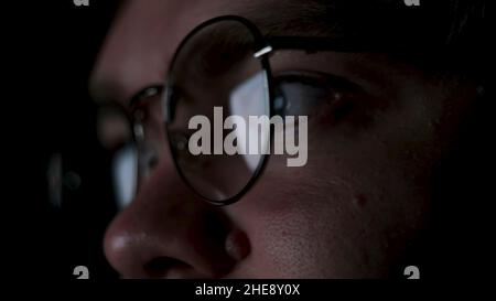 Close up of tired man putting off glasses and rubbing his eyes. The reflection of the screen in the glasses of a genius or nerd working at night. Stock Photo