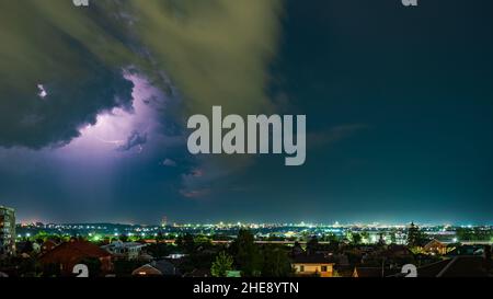 Thunderstorm over the city at night, bright lightning among dense clouds Stock Photo