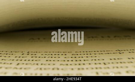 Close up of an open book with a gap between two pages. Camera moving along the printed lines of the page on black background, concept of reading. Stock Photo