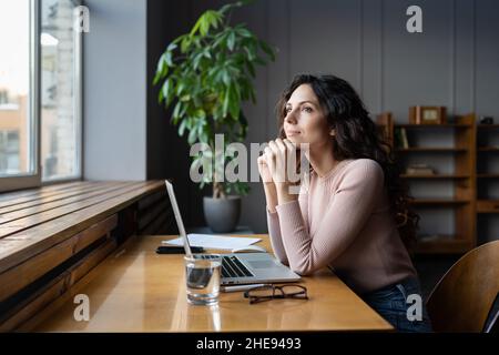 Wellbeing at work. Young dreamy female employee enjoying good window view while working in office Stock Photo
