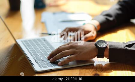 Cropped image of a businessman's hands typing on laptop keyboard at his office desk. searching, browsing internet, working online. Stock Photo