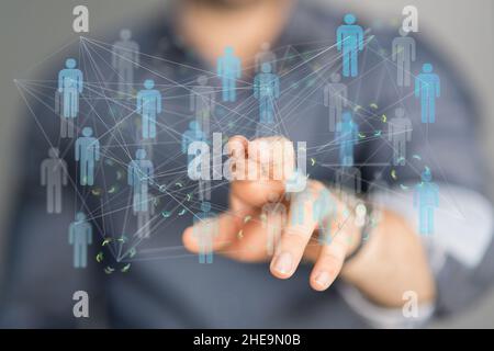 Shallow focus of a human hand pointing on interconnected human icons, teamwork concept Stock Photo