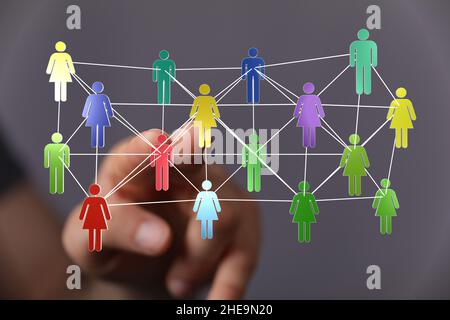 Shallow focus of a human hand pointing on colorful human icons, team networking concept Stock Photo