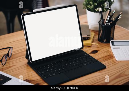 A white screen tablet computer placed on the desk at work. Can put text or media in the area on the white screen. Stock Photo