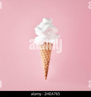 Ice cream cone with shaving foam on pink background. April Fool's Day minimalistic creative concept. Stock Photo