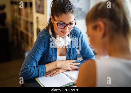 Happy young university students studying with books in library. Stock Photo