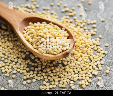 Raw Couscous in wooden spoon on the grey concrete background Stock Photo
