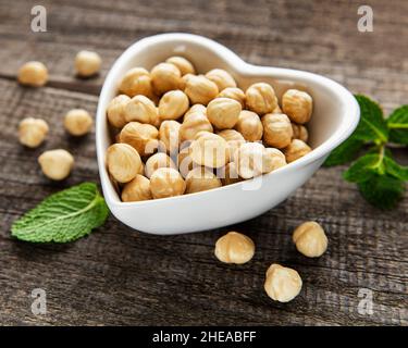 Peeled hazelnuts in a bowl on old wooden background Stock Photo