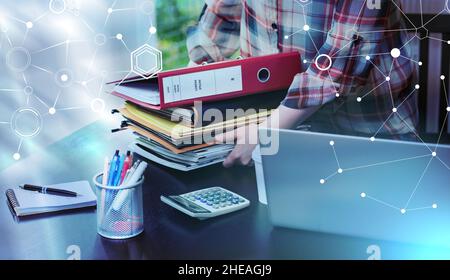Businesswoman putting a stack of binders and folders on her desk; light effect Stock Photo