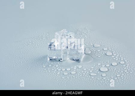 Three ice cubes with drops of water on a gray background Stock Photo