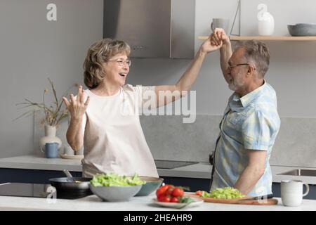 Happy middle aged couple dancing in kitchen. Stock Photo