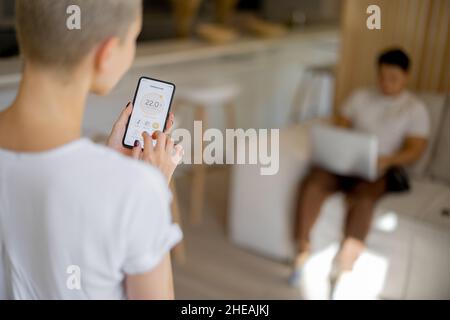Couple using app of smart home on smartphone Stock Photo