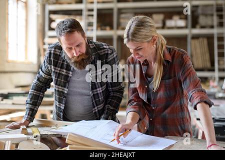 Two carpenters man and woman talking about design of products. Small business concept. Stock Photo