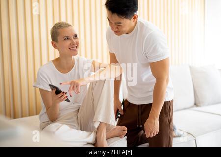 Multiracial couple sit and talk on sofa at home Stock Photo