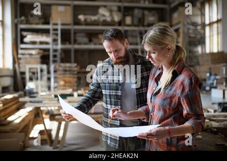 Two carpenters man and woman talking about design of products. Small business concept. Stock Photo