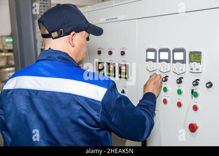 Hand pressing on green button of the machine in the factory Stock Photo