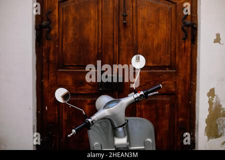 Shallow depth of field (selective focus) details with a scooter with a wooden door in the background. Stock Photo