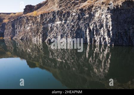 Basaltic rock formations and the so called emerald lake in the transylvanian town of Racos, Romania, on a sunny autumn day. Stock Photo