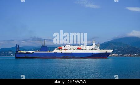 Huge passenger car-railway ferry enters the city against the backdrop of mountains on a sunny day, Batumi, Georgia Stock Photo