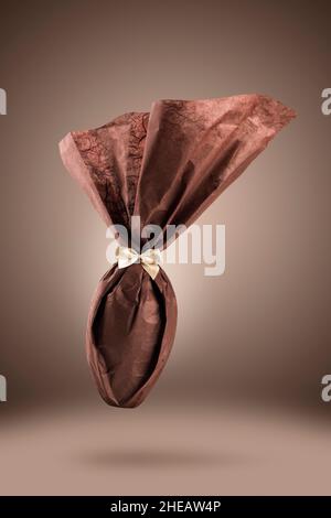 Chocolate easter egg packed with elegant brown paper on brown background Stock Photo