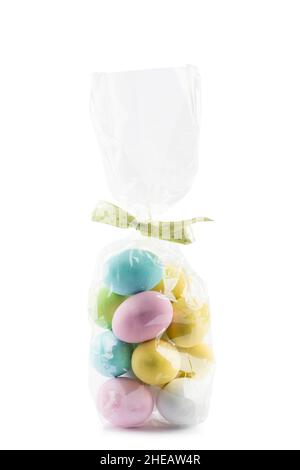 Small colorful easter eggs in transparent bag on white background Stock Photo