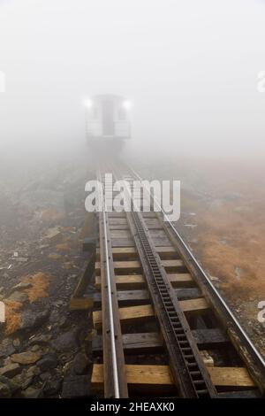 Trackbed and rear view of a carriage on the Mount Washington Cog Railway, Mount Washington, New Hampshire, New England, USA, viewed in thick fog Stock Photo