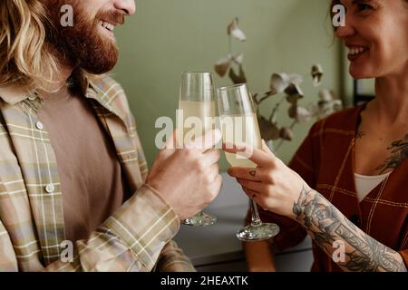Close-up of young happy couple toasting with glasses of champagne standing in the room Stock Photo