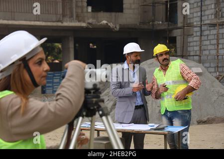 Indian construction workers. Construction engineers working on a builder construction site wearing hardhat. Analyzing blueprint. Stock Photo