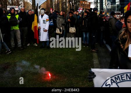 Brussels, Belgium. 9th Jan, 2022. A protester wearing an Anonymous mask holds a Belgian flag during a demonstration against mandatory Covid-19 vaccination and other government measures to contain the spread of Covid-19 in Brussels, Belgium, January 9, 2022. (Credit Image: © Valeria Mongelli/ZUMA Press Wire) Stock Photo