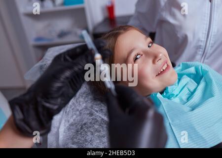Little girl at dentist office, getting local anesthesia injection into gums. Cropped view of the dentist numbing gums for dental work. Pediatric denta Stock Photo