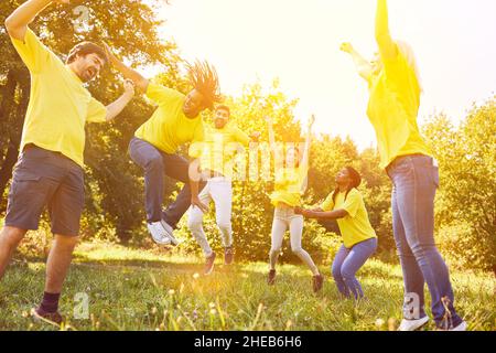 Happy team cheers together and jumps on a meadow after victory Stock Photo