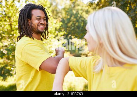 Young man and young woman at elbows greeting for distance and safety in summer Stock Photo