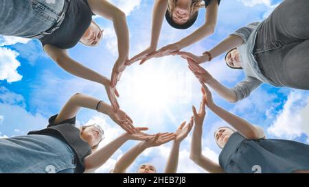 Friends make a circle with their palms against the blue sky. Stock Photo
