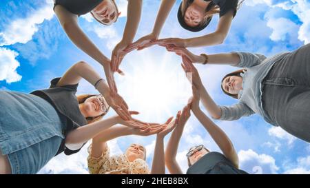 Friends make a circle with their palms against the blue sky. Stock Photo