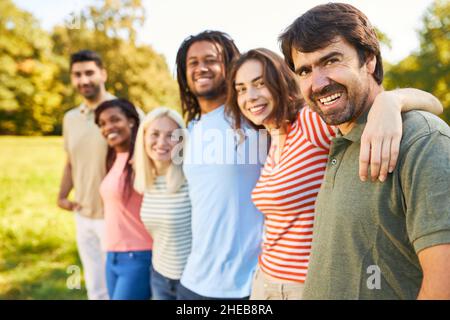 Diverse happy group of friends hugging in nature in summer Stock Photo