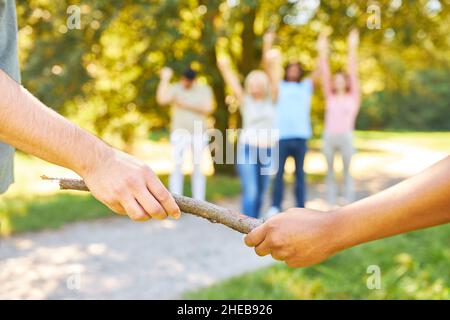 Handover of the baton in the relay race as a team building exercise in the summer in nature Stock Photo