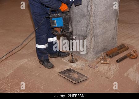 Worker with jackhammer. Male worker drilling and repairing concrete surface with jackhammer. Professional worker. Stock Photo