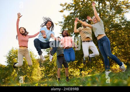 Young people have fun together and jump and hop on a meadow in summer Stock Photo