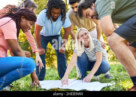 Group of friends playing a terrain game with a map in a team building workshop Stock Photo