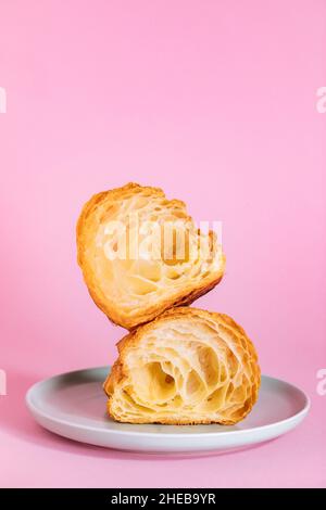 Croissant cut in two pieces isolated on purple background. Simple and elegant concept. Stock Photo