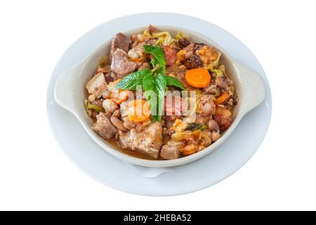 Delicious traditional Portuguese dish feijoada and sewn with smoked sausage with carrots with cabbage and mint leaves. On isolated white background. Stock Photo